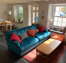 A living room with a blue sofa and coffee table next to a dining table with four chairs at Kernyk in Carn Brea near Pool