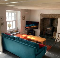 A living room with a teal sofa a wooden coffee table a wood burning stove and a rocking chair at Kernyk in Carn Brea near Pool