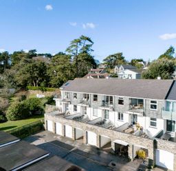 A row of townhouses with balconies and garages in front surrounded by trees at Slipway 14 in Rock