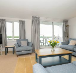 A living room with blue sofas a wooden coffee table with yellow flowers and a television at Slipway 14 in Rock