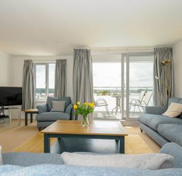 A living room with sofas a coffee table TV and balcony doors at Slipway 14 in Rock