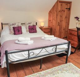 A bedroom with a double bed two bedside tables wooden wardrobe dressing table and chair at Ty Llugwy in Capel Curig near Betws-Y-Coed