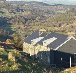 A house with a roof and chimney on a hillside at Ty Llugwy in Capel Curig near Betws-Y-Coed