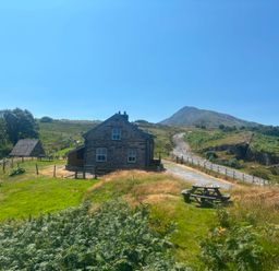 A house with a mountain in the background and a picnic table at Ty Siabod in Capel Curig near Betws-Y-Coed