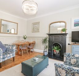 A living room with a fireplace and dining area at 11A High Street in Jedburgh