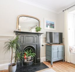 A living room with a fireplace and television at 11A High Street in Jedburgh