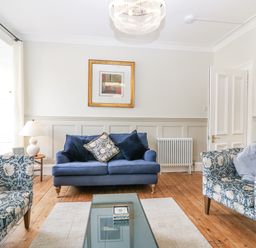 A living room with a blue sofa and patterned armchairs at 11A High Street in Jedburgh
