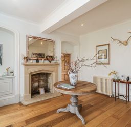 A living room with a fireplace and a table at Cotswold House in Moreton-In-Marsh