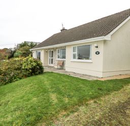 A single story house with a tiled roof and garden at Lakeview Lodge in Knockmore County Mayo