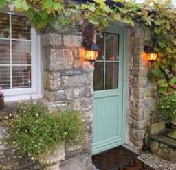 Entrance door with lights stone walls plants and grapevine at Little Cloud Nash near Cowbridge
