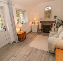 A living room with a striped sofa pillows a fireplace wooden furniture and lamps at Little Cloud Nash near Cowbridge