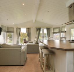 An open plan living and kitchen area with sofas and bar stools at Lakeview Lodge in Forton near Garstang