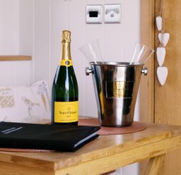 A table with a champagne bottle and glasses at Bonnie's Shepherds Hut at Shepherds Lodge Retreat and Wellness Bottesford near Redmile and Vale of Belvoir