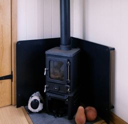 A wood stove with a black screen and a stuffed animal at Bonnie's Shepherds Hut at Shepherds Lodge Retreat and Wellness, Bottesford near Redmile and Vale of Belvoir