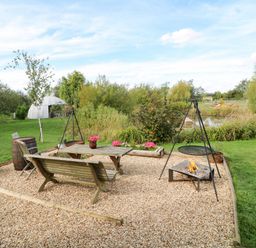 A garden area with a table, chairs, and a fire pit at Lillie's Shepherds Hut at Shepherds Lodge Retreat and Wellness, Bottesford near Redmile and Vale of Belvoir
