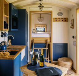 A kitchen with a dining table and champagne at Lillie's Shepherds Hut at Shepherds Lodge Retreat and Wellness Bottesford near Redmile and Vale of Belvoir