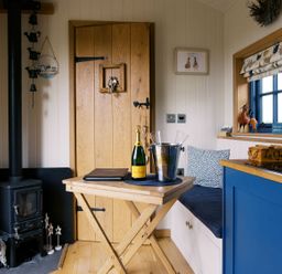 A kitchen with a wooden table and stove at Lillie's Shepherds Hut at Shepherds Lodge Retreat and Wellness Bottesford near Redmile and Vale of Belvoir