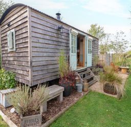 A shepherd's hut with steps and plants at Herbie's Shepherds Hut at Shepherds Lodge Retreat and Wellness in Bottesford near Redmile and Vale of Belvoir