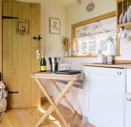 A kitchen with a table and champagne at Herbie's Shepherds Hut at Shepherds Lodge Retreat and Wellness Bottesford near Redmile and Vale of Belvoir