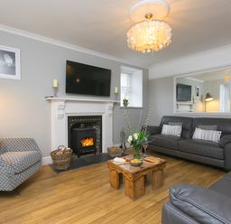 A living room with a fireplace a wooden coffee table and leather sofas at Captain's Walk in Newquay