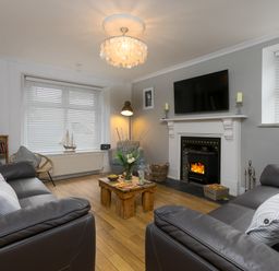 A living room with two leather sofas a wooden coffee table fireplace and a television at Captains Walk in Newquay