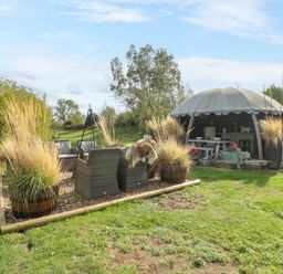 A garden with outdoor seating and planters at Poppie's Shepherds Hut at Shepherds Lodge Retreat and Wellness Bottesford near Redmile and Vale of Belvoir