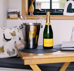 A dining table with champagne and glasses at Poppie's Shepherds Hut at Shepherds Lodge Retreat and Wellness Bottesford near Redmile and Vale of Belvoir