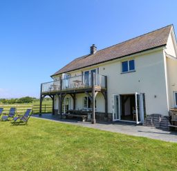 A house with a wooden balcony and patio chairs on a lawn at Yr Adfa Llangeitho near Tregaron