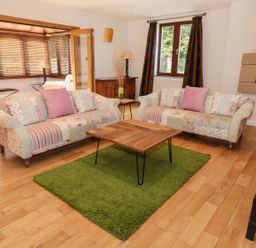 A living room with two floral sofas a wooden coffee table on a green rug and wooden floors at Walworth Castle Lodge in Walworth near Darlington