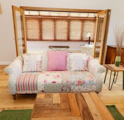 A living room with a patchwork patterned sofa pillows wooden coffee table and wooden sideboard at Walworth Castle Lodge Walworth near Darlington