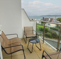 A balcony with chairs and a table at Seaview in Benllech near Red Wharf Bay