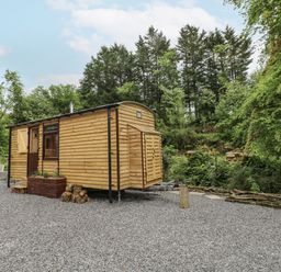 A tiny house with wood exterior and gravel surface at The Hamper in Felingwm near Carmarthen