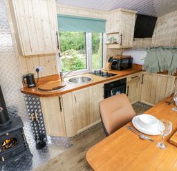 A kitchen with wooden cabinets and a dining table at The Hamper in Felingwm near Carmarthen