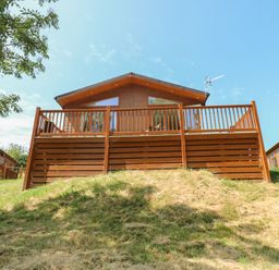 A log cabin with a deck on a hill at Finnbars Lodge in Richmond