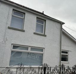 A white building with three windows and a black wrought iron fence in front at Meillion in Hirwaun