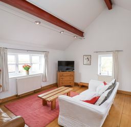 A living room with a white sofa red cushions wooden coffee table and television at The Barn - Poplar Farm in Lower Dunsforth near Boroughbridge