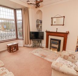 A living room with a fireplace television and a large bay window at Glan Yr Afon in Ystradgynlais
