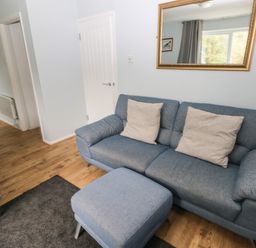 A living room with blue couches a gray rug and a mirror on the wall at Kittiwake Apartment 22 in Little Haven near Broad Haven