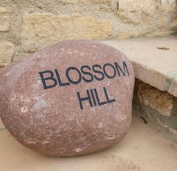 A stone with the words Blossom Hill engraved placed on a tiled step near a stone wall at Blossom Hill near Witney