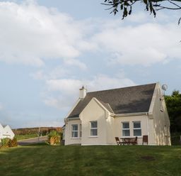 A house with a sloped roof and outdoor chairs on a grassy lawn at Horn Head View in Carrigart County Donegal