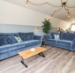 A living room with two blue sofas and a wooden coffee table at La Bella Vista in Kilkhampton