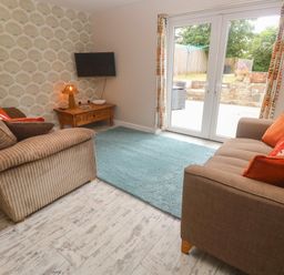 A living room with a sofa and television at The Packing House in Rosudgeon