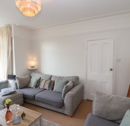 A living room with gray sofas a wooden coffee table and a window with curtains at Trackside Ruswarp