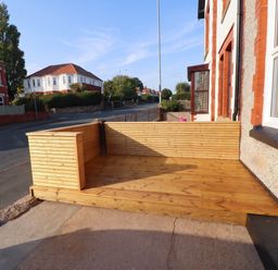 A wooden decking area next to the street at Flat 1 Rhos-On-Sea