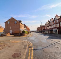 A street view with residential buildings and ocean in the background at Flat 1 Rhos-On-Sea