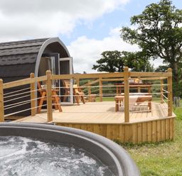 An outdoor area with a deck, hot tub, and seating at Under Oak Pod in Totnes