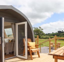 A pod with chairs and a table on a deck at Under Oak Pod in Totnes