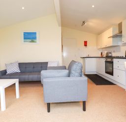 A living room with a sofa and kitchen area at 161 Atlantic Bay Holiday Park, Padstow