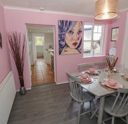 A dining room with a set table and a painting on the wall at Cherry Blossom Cottage in Stratford-Upon-Avon