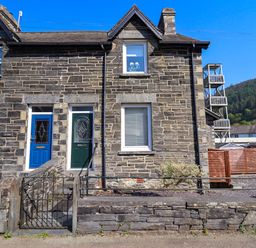 A stone exterior house with two colored front doors and metal gates at Dola in Pentre Du near Betws-Y-Coed